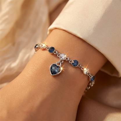 Pulseira de corrente com pingente de coração em prata e safira, da marca Rose & Oliver, exibida em close na imagem.