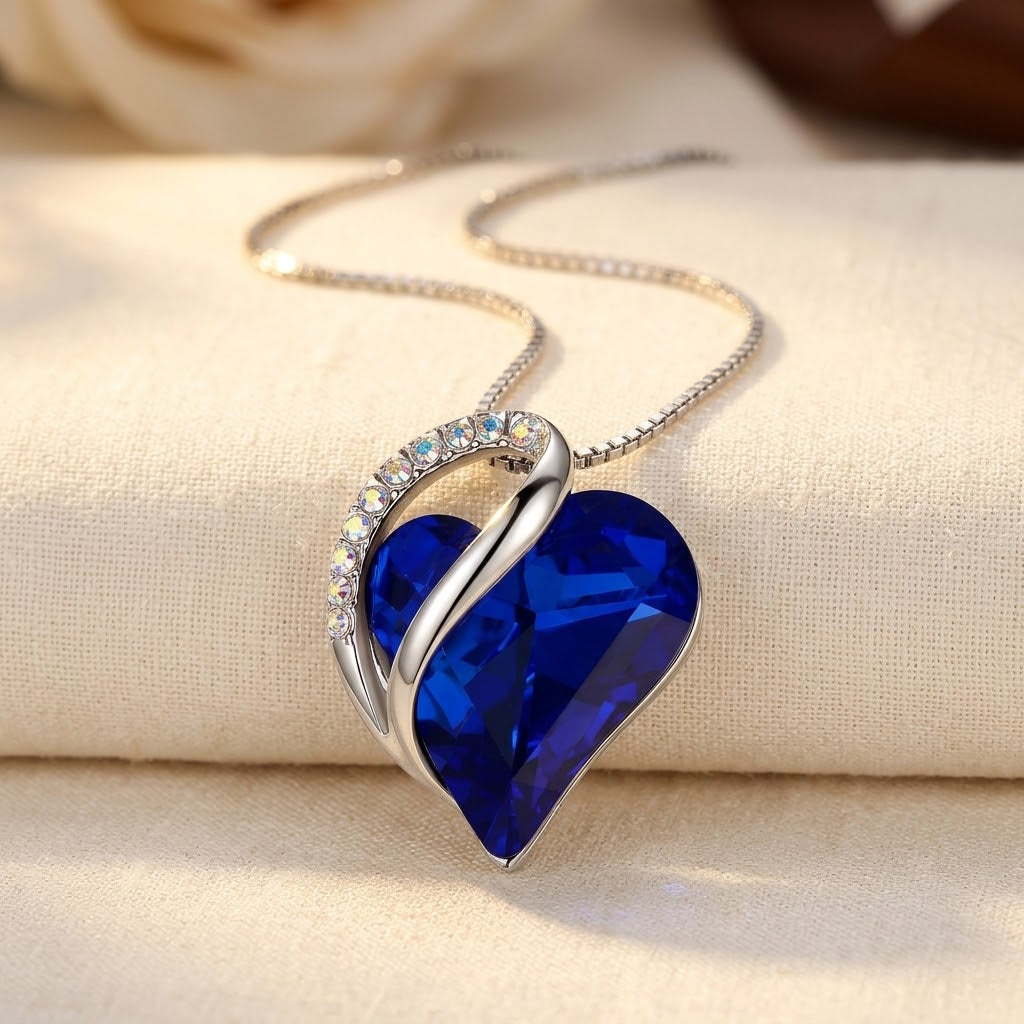 Colar de prata com coração e safira azul, joia delicada da marca Rose & Oliver, exibido com detalhes no colar.