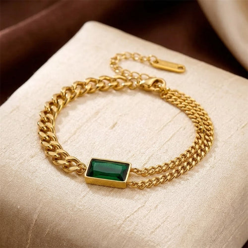 Pulseira de ouro e esmeralda Rose & Oliver, com corrente de barra e detalhes elegantes, visível na imagem.