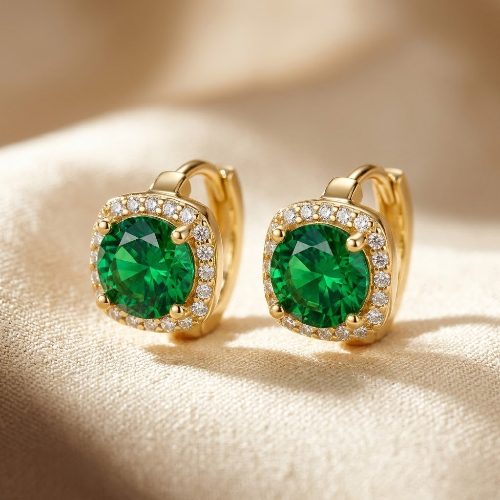 Brincos de argola dourados com detalhes de esmeralda em halo, da marca Rose & Oliver, exibidos na imagem.